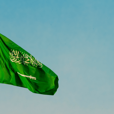 علم المملكة العربية السعودية يرفرف على خلفية السماء، رمز الهوية الوطنية والتطلعات المستقبلية ضمن رؤية 2030.